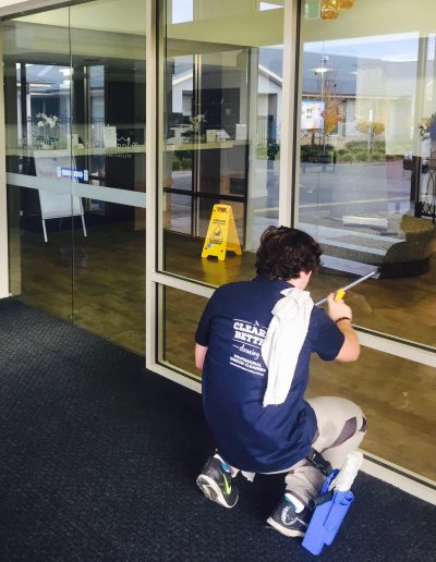 Professional window cleaner in navy blue uniform cleans the window at an aged care facility in Melbourne